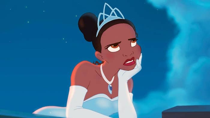Personaje animado con tiara blanca y vestido elegante, apoyando la cabeza en su mano, mirando hacia arriba pensativamente