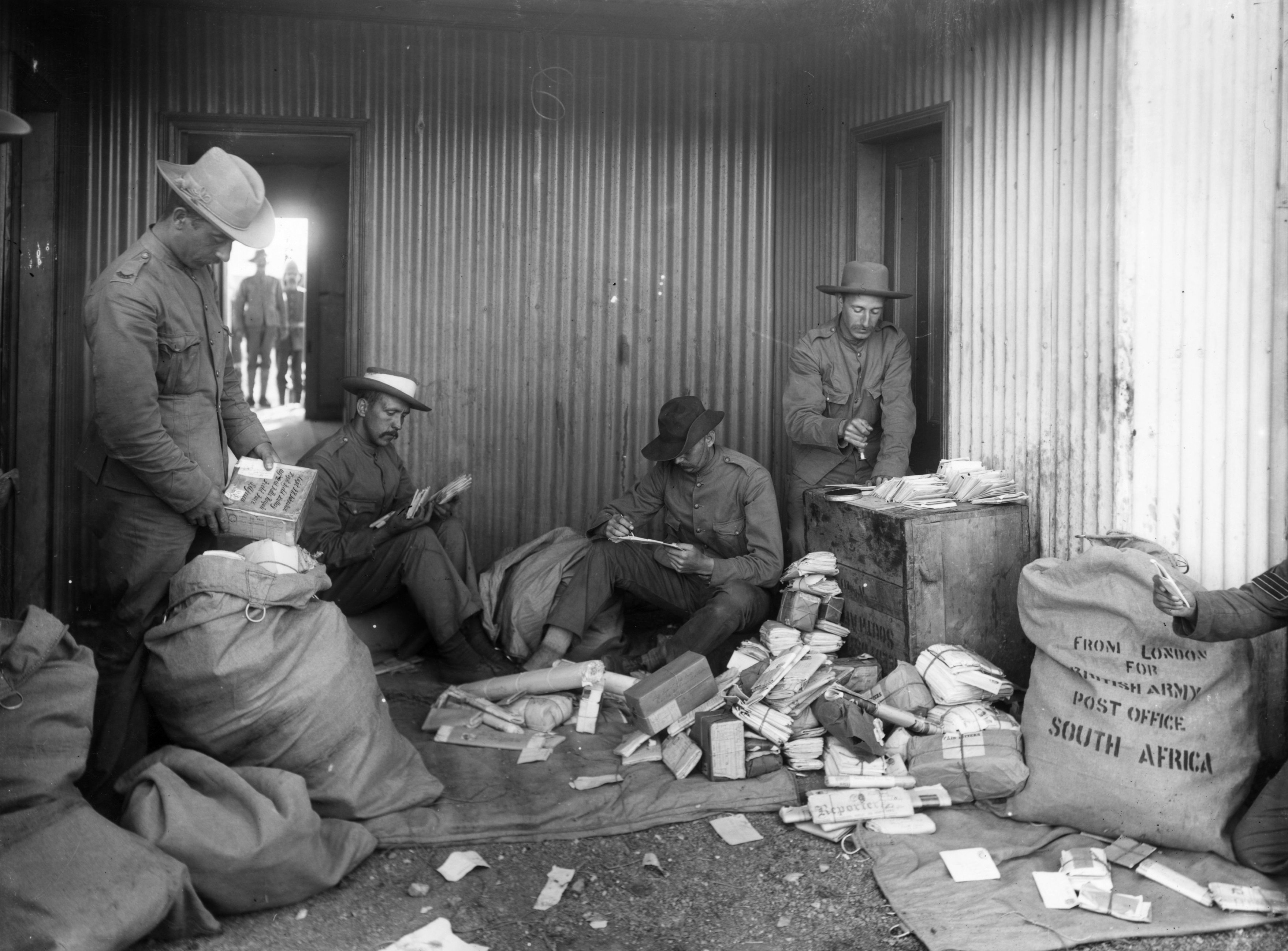 Historical photograph  of soldiers successful  a corrugated metallic  gathering  sorting done  message  connected  the floor. Bags labeled "South Africa" situation   them