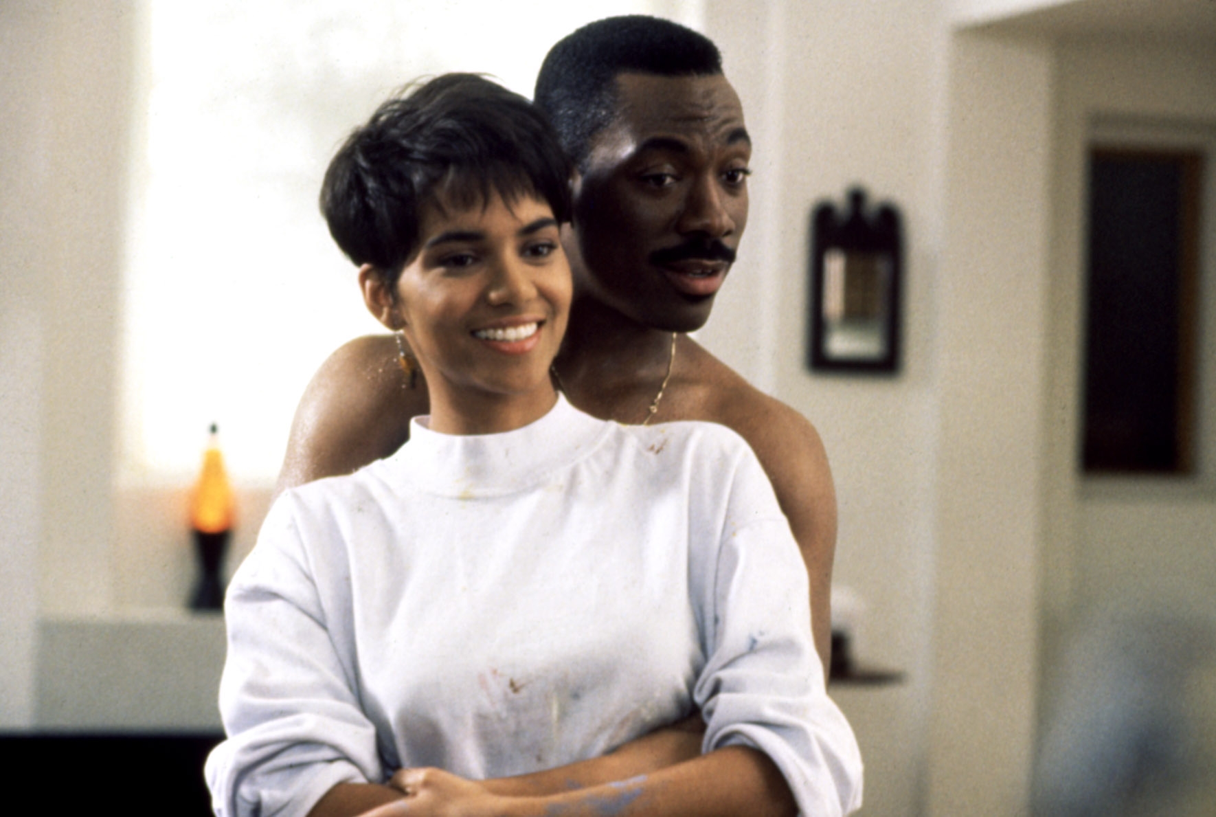 A smiling mates stands unneurotic successful a warmly-lit room; the antheral hugs the pistillate from behind