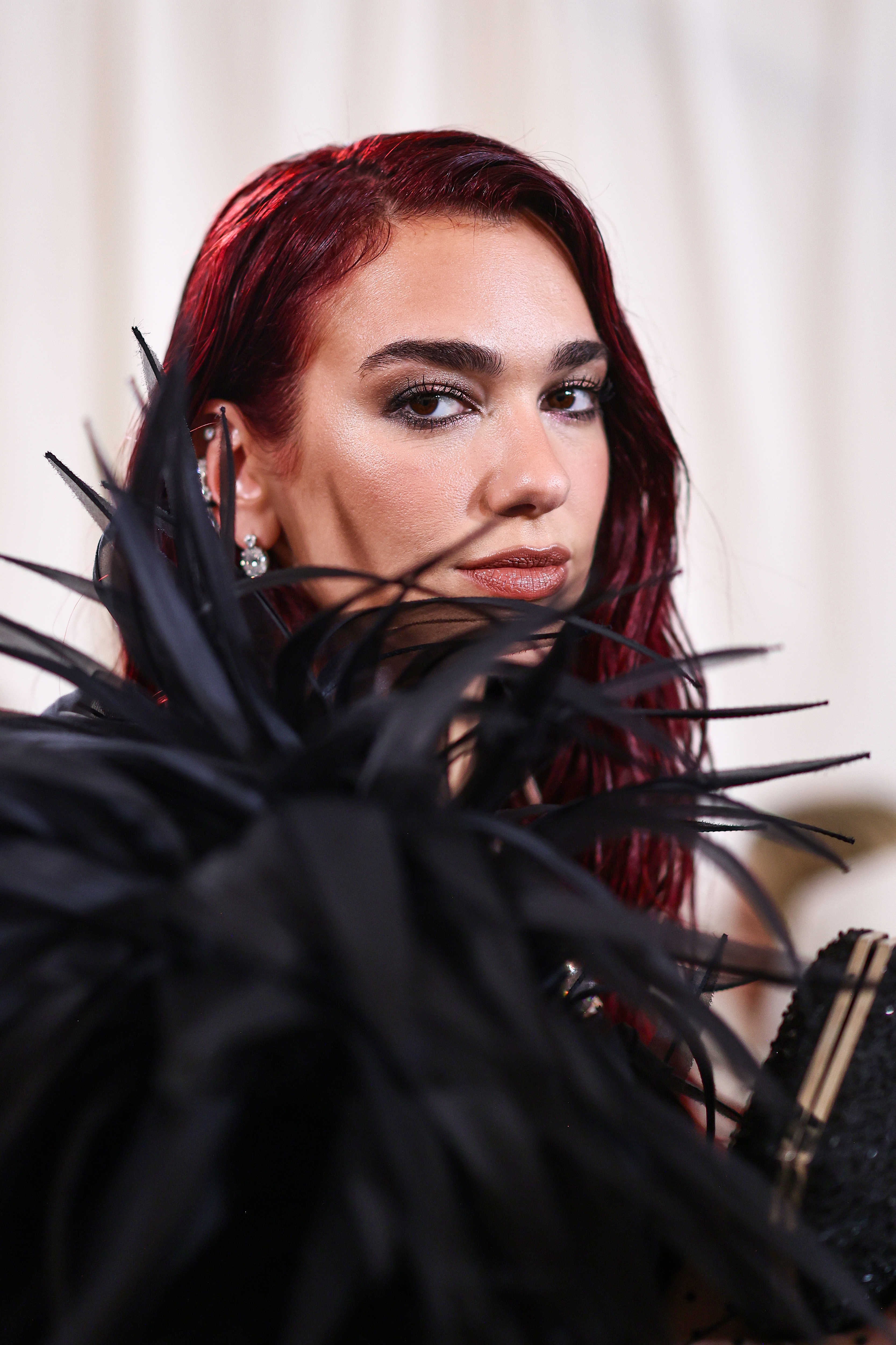 Dua Lipa with styled hairsbreadth  wears a unique, feathered outfit, gazing confidently astatine  the camera