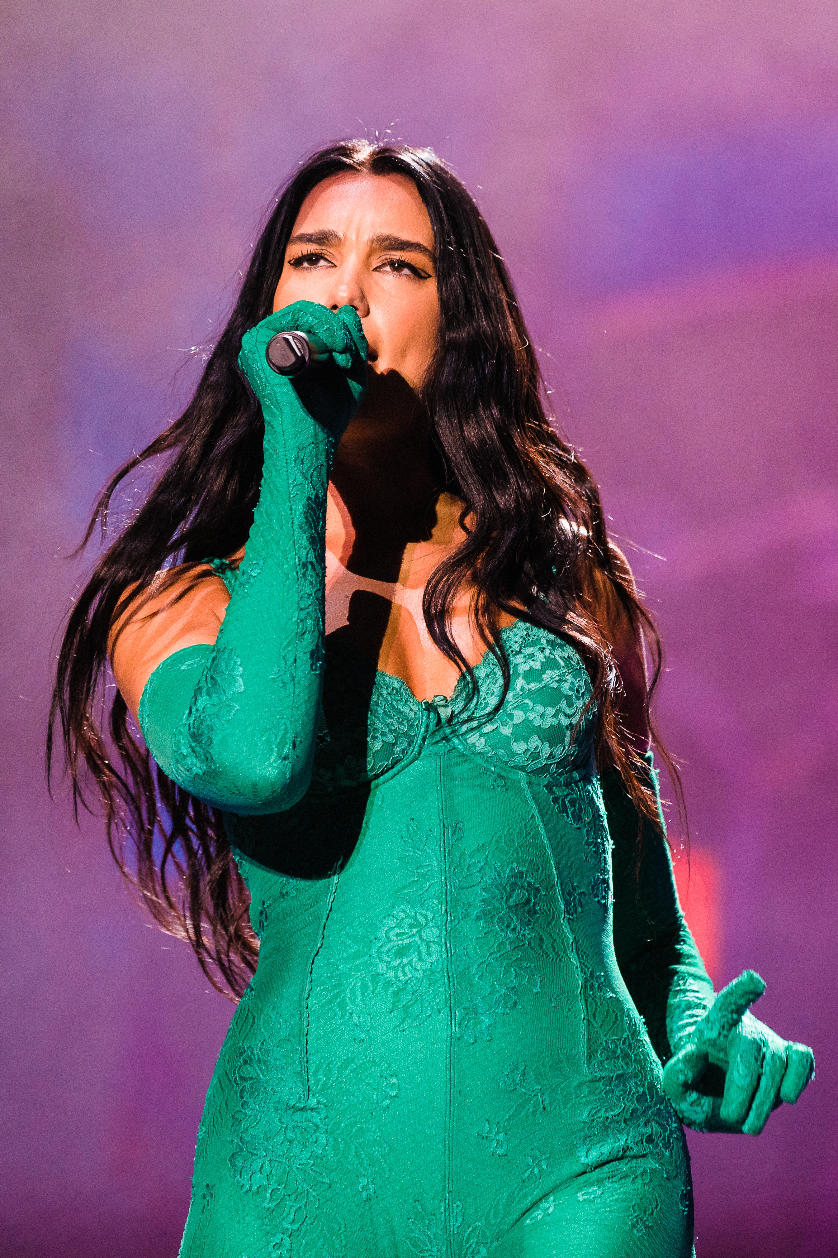 Dua Lipa performs connected  signifier    wearing a form-fitting lace outfit with gloves, holding a microphone