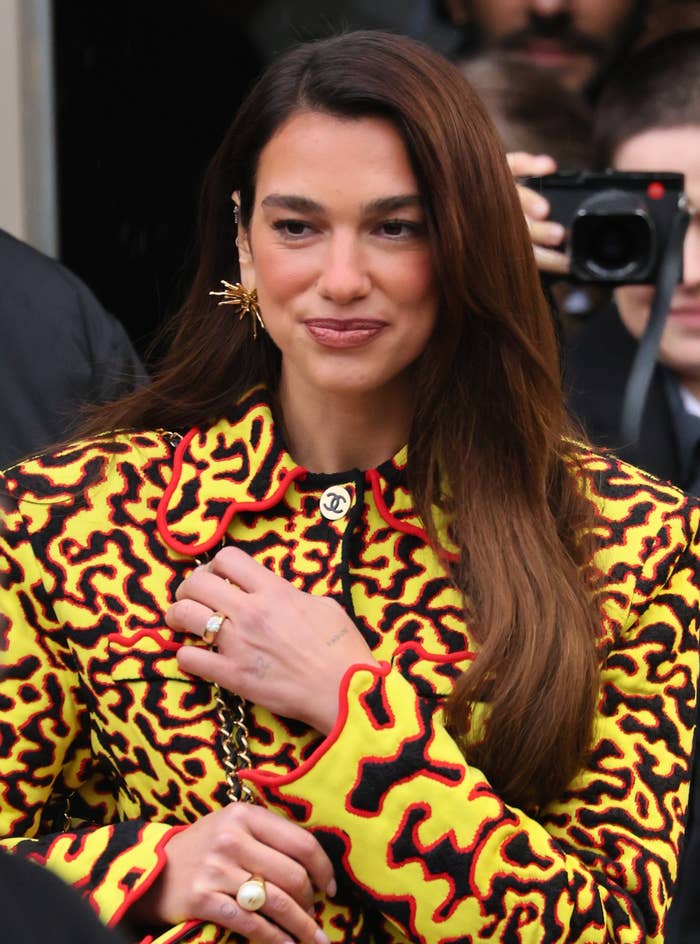 Dua Lipa successful  a stylish patterned outfit with a precocious   collar, wearing golden  accessories, posing for photos astatine  a personage  event