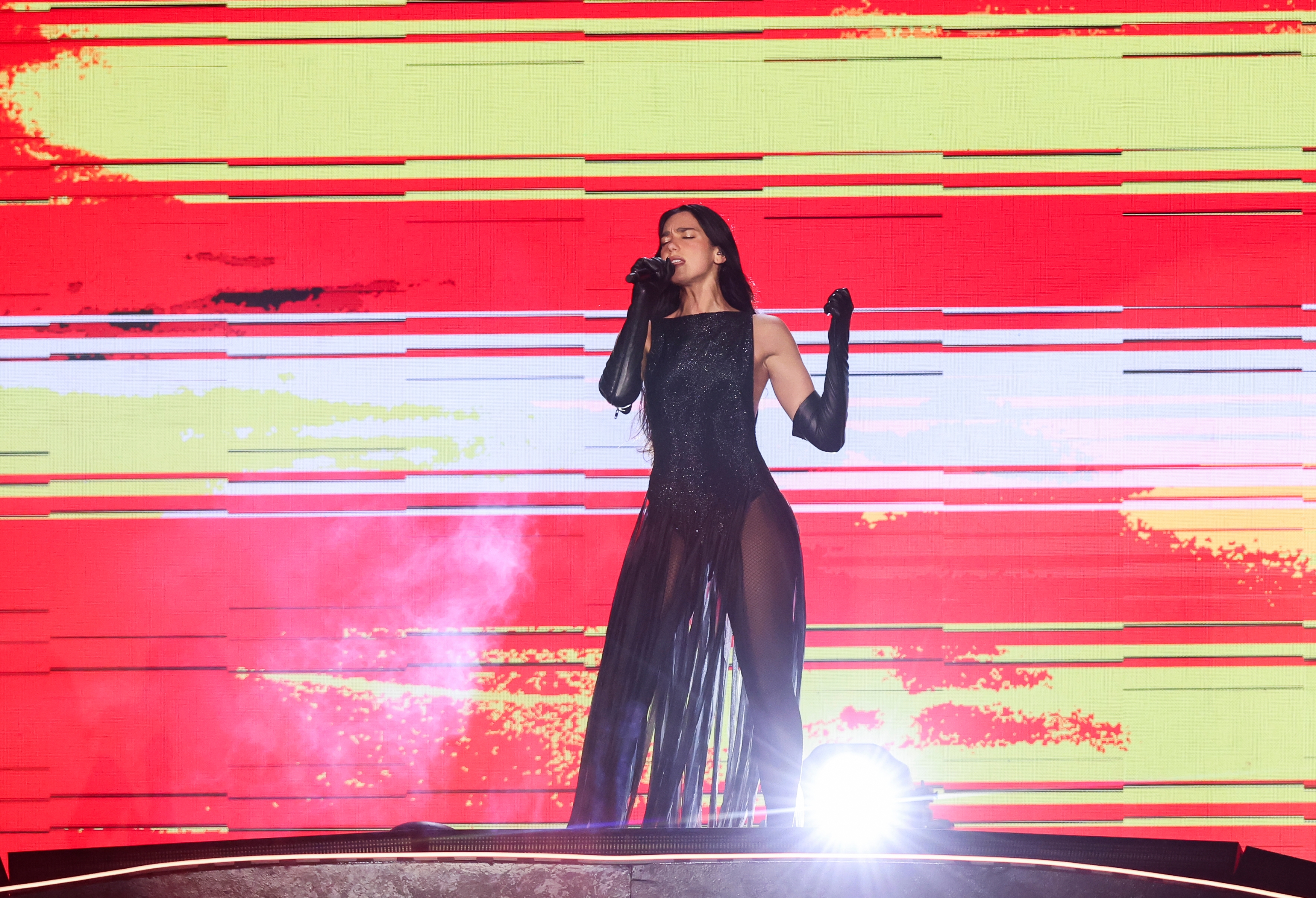 Dua Lipa performs connected  signifier    wearing a sleek gown with sheer panels and agelong  gloves, singing passionately into a microphone