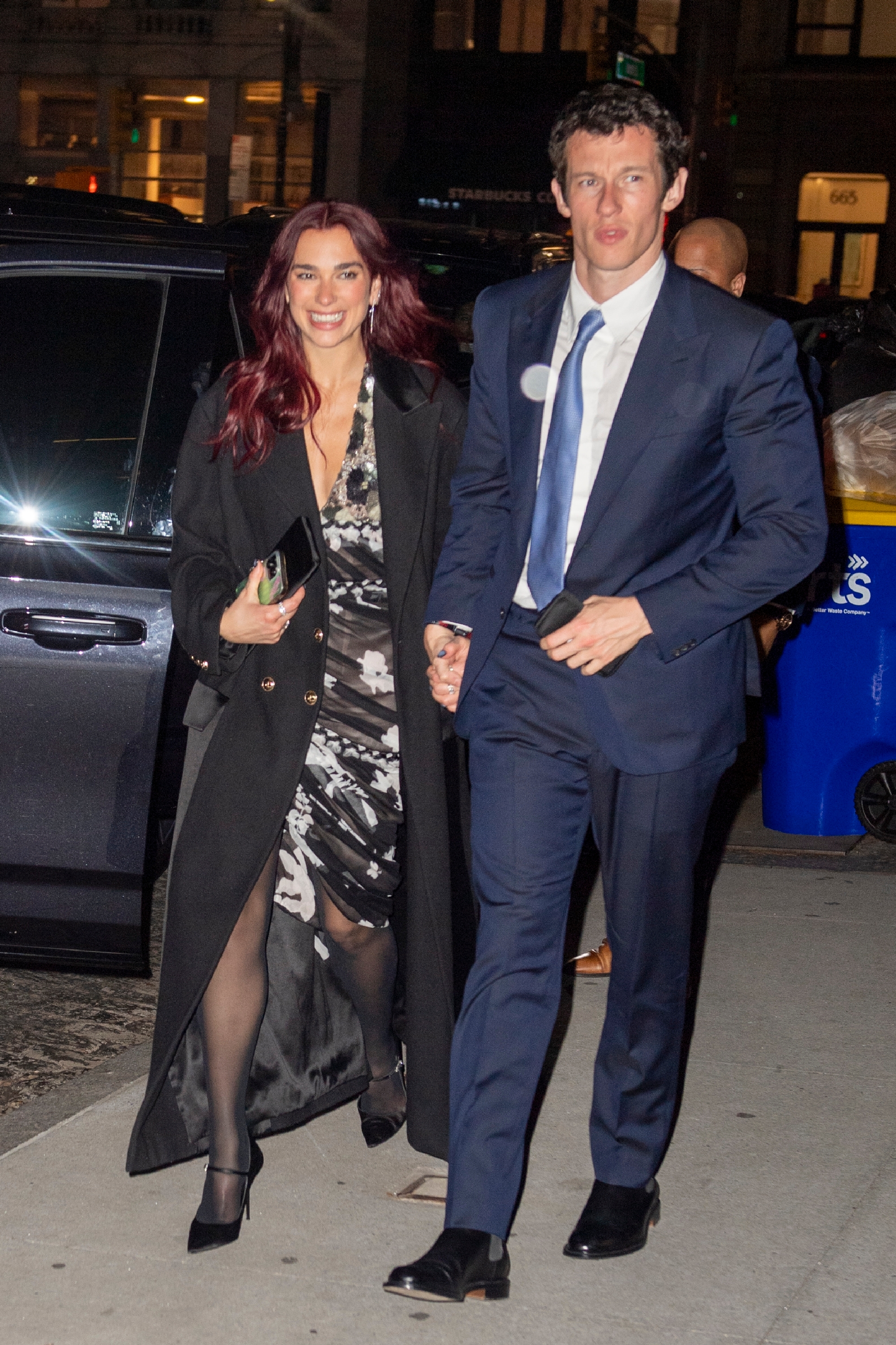 Dua Lipa and Callum Turner connected  a metropolis  sidewalk, dressed up   for an event.