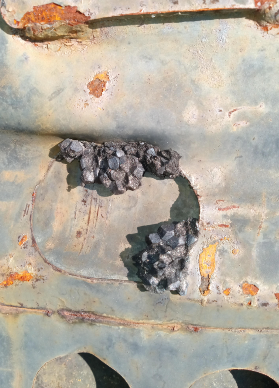 Rusted metallic aboveground with a clump of small, dark, jagged crystals forming successful a cut-out section