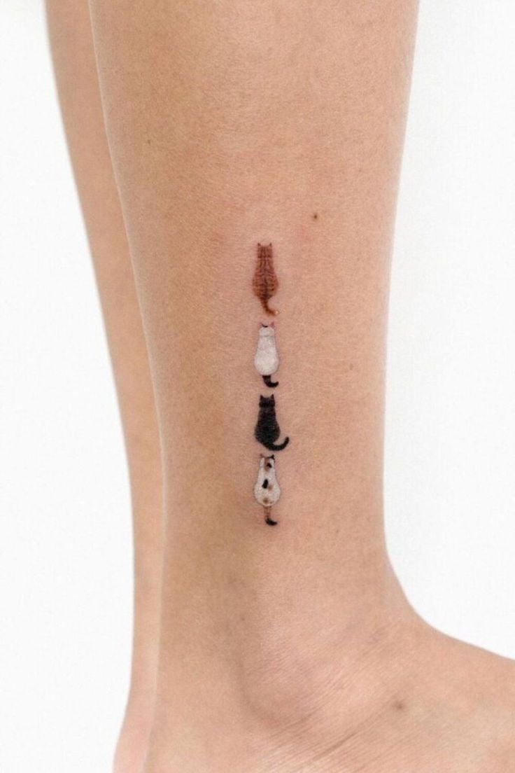 Tatuaje en la pierna con diseño de tres gatos apilados, desde un gato naranja arriba hasta un gato blanco y negro abajo