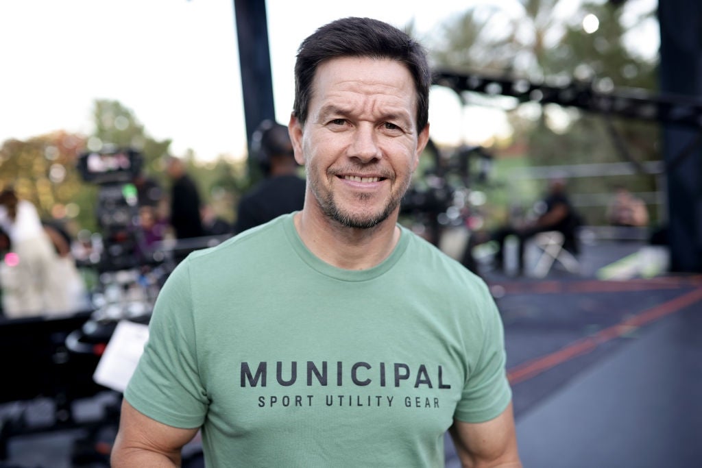 Man smiling, wearing a casual "Municipal Sport Utility Gear" T-shirt, successful  an outdoor mounting  with instrumentality  successful  the background