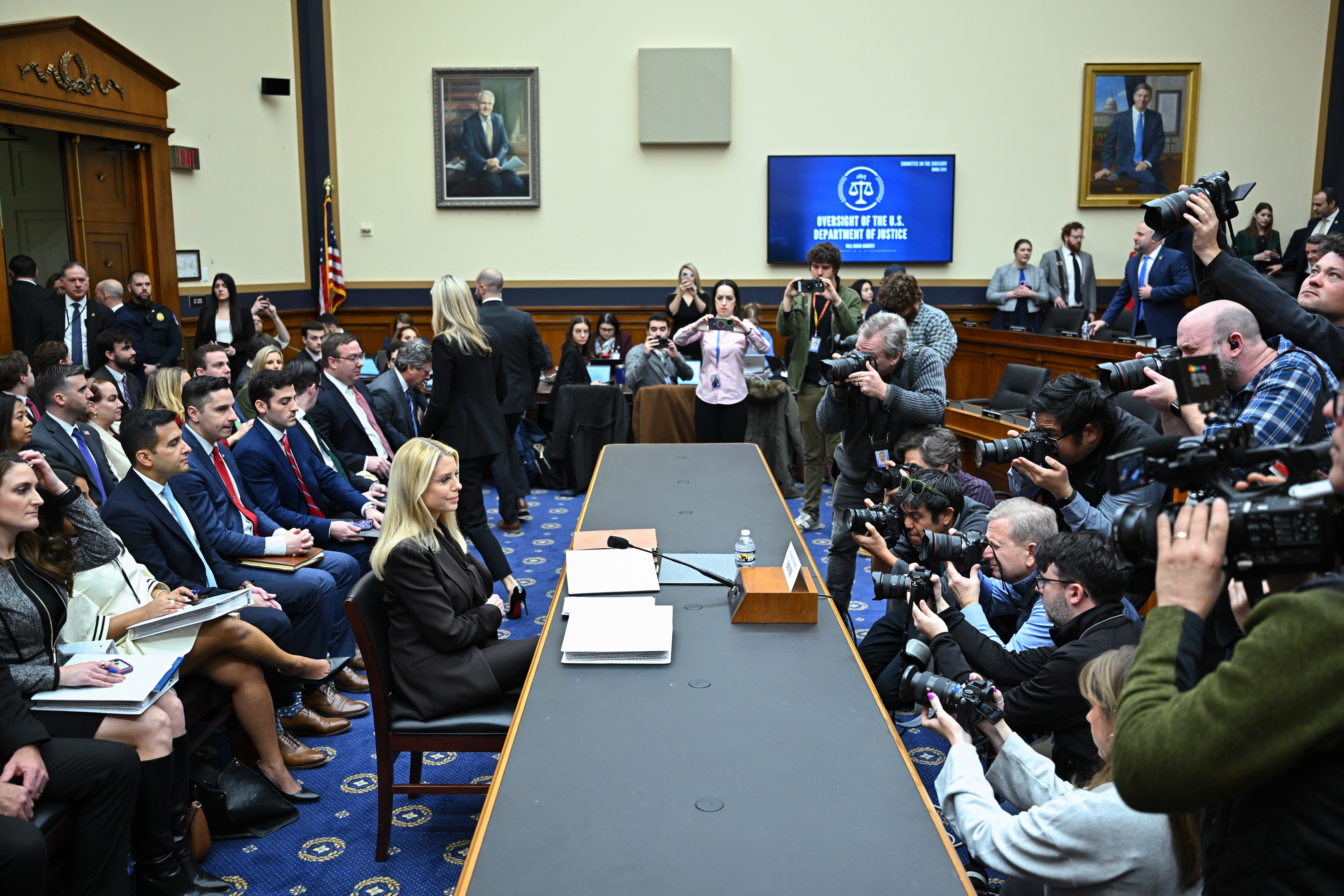 Congressional proceeding  with a witnesser  seated astatine  a table, surrounded by journalists and cameras, occurring successful  a country   with attendees and officials
