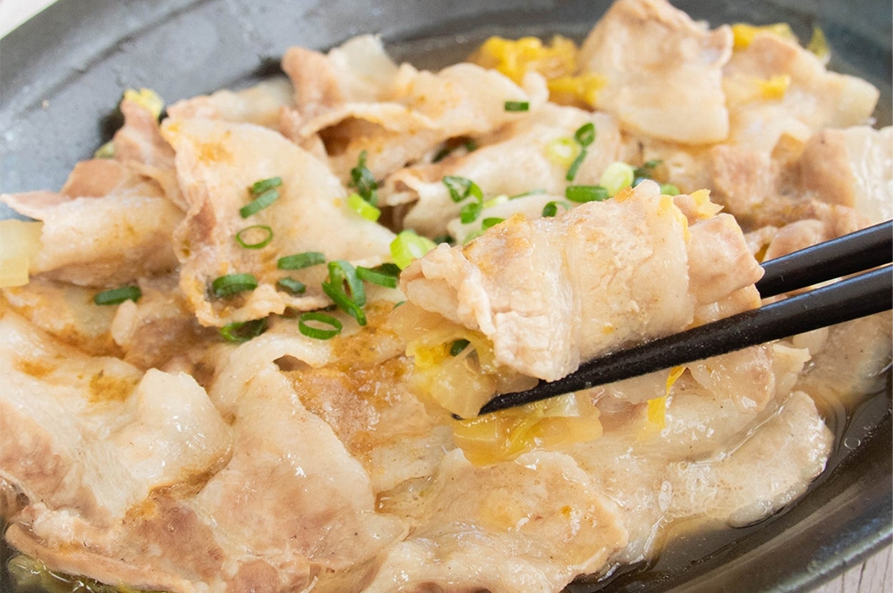 豚肉と玉ねぎが盛られた皿。刻みネギがトッピングされている。