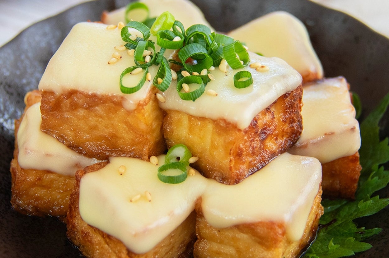 めんつゆを絡めて焼いた厚揚げの上にチーズと小ネギがのった料理。