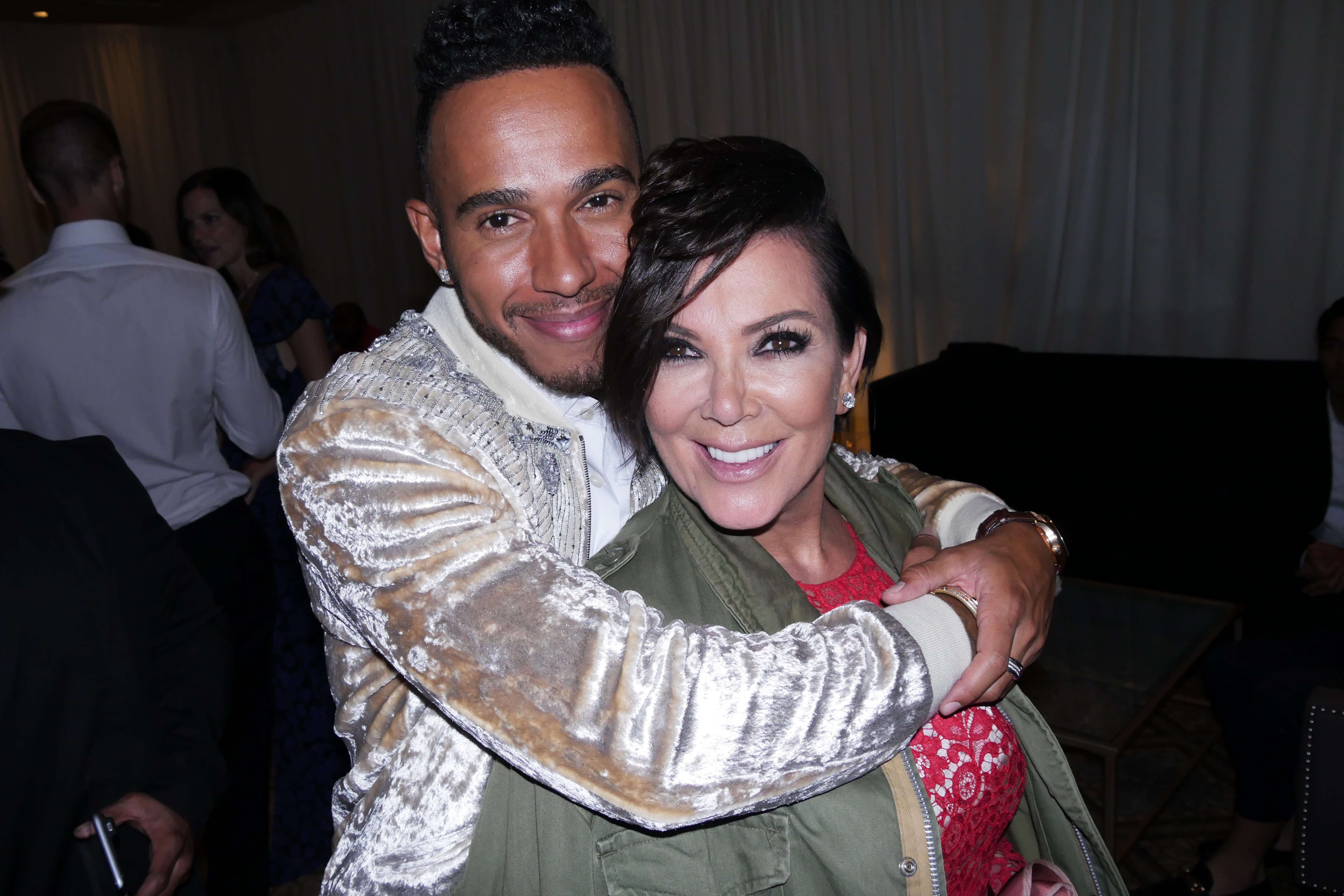 Two radical   smiling and embracing, with 1  wearing a shiny overgarment   and the different   successful  a casual greenish  outfit