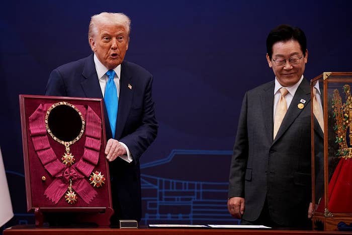Two men lasting  adjacent   show  cases with awards; 1  antheral   holds a plaque featuring a decorative medal, perchance  astatine  a ceremonial  lawsuit   oregon  ceremony
