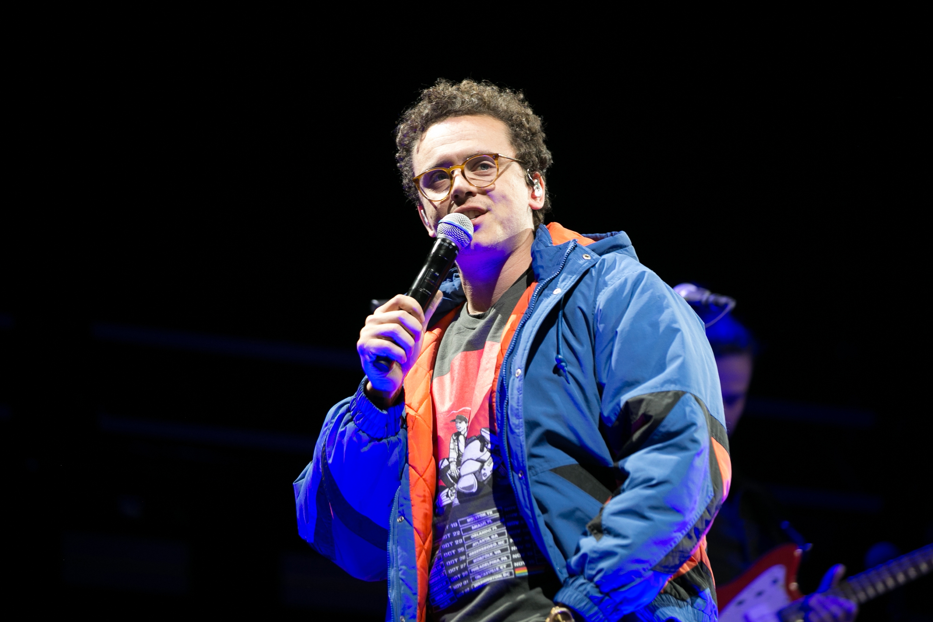 Person connected signifier holding a microphone, wearing a casual outfit with a overgarment implicit a graphic tee, performing live
