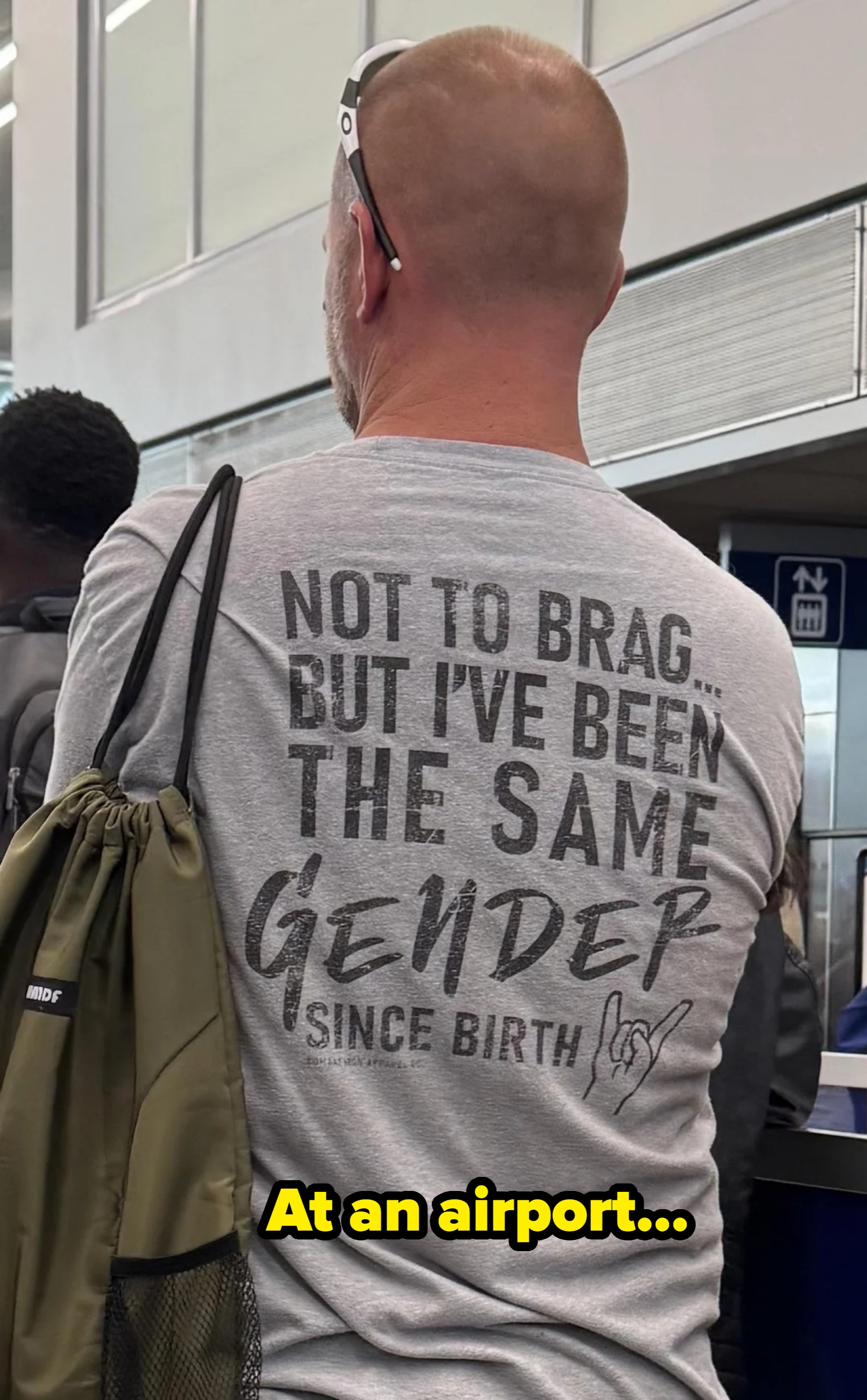 Man with shaved head, sunglasses connected  head, astatine  airport. Shirt reads, "Not to brag... but I've been the aforesaid  sex  since birth."