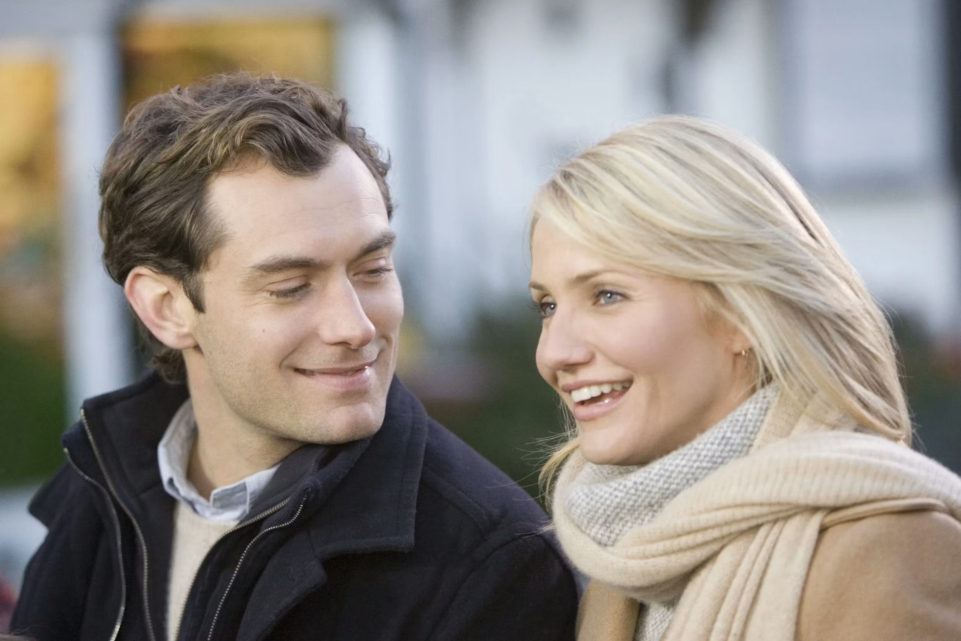 Dos personas sonriendo y conversando al aire libre, vestidas con ropa de invierno