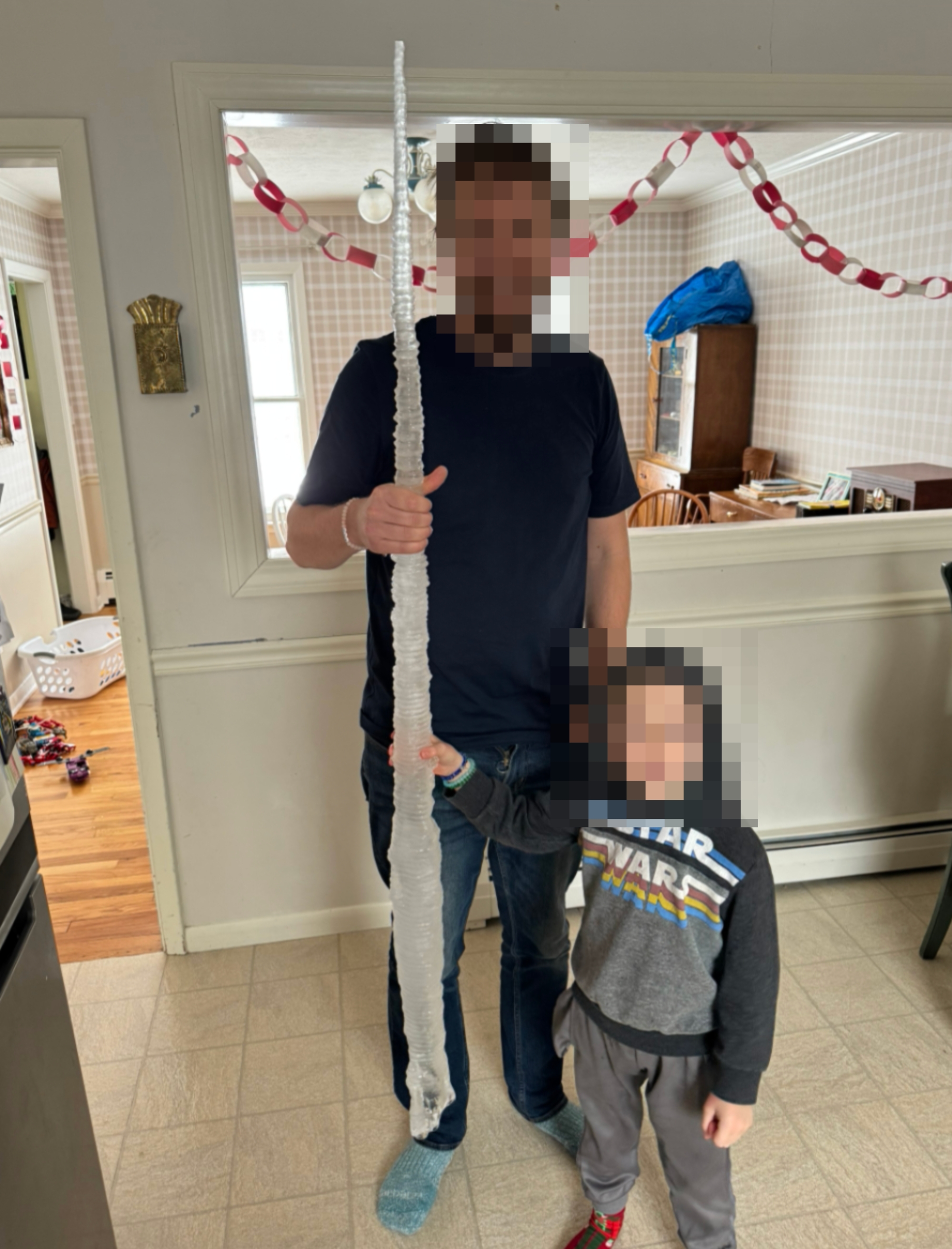 An big and kid wrong a location clasp a ample icicle, smiling. The kid wears a hooded "Star Wars" sweatshirt. Festive decorations are visible