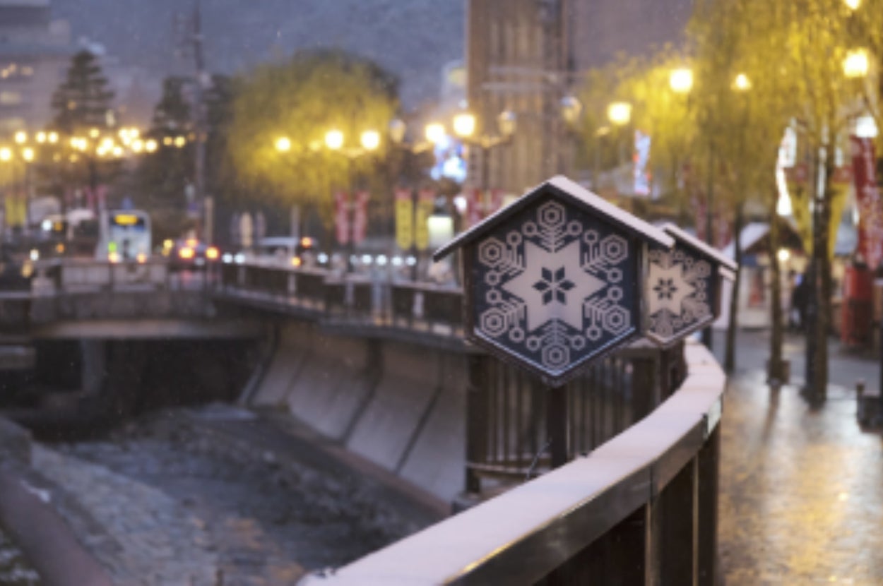 街灯に照らされた雪の積もった川沿いの橋、冬の夜景。