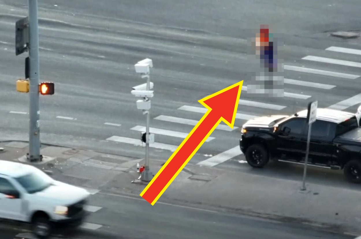 マリオのコスプレをした人物が交差点の信号機にぶら下がっている様子。