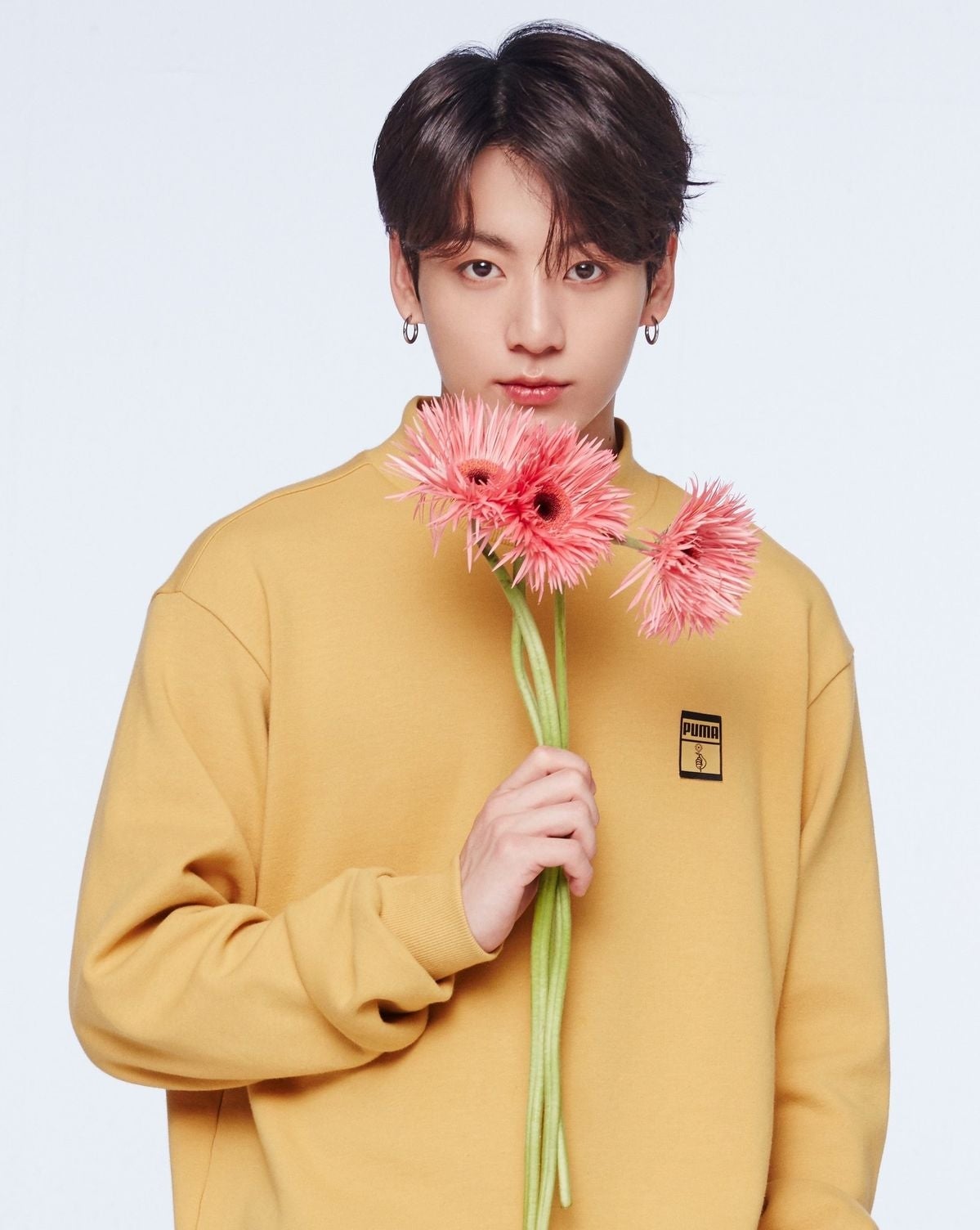 Persona sosteniendo flores, vestido con un suéter de estilo casual