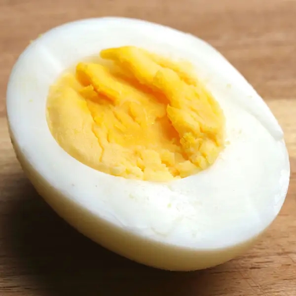 Half of a hard-boiled ovum with a steadfast yolk displayed connected a woody surface