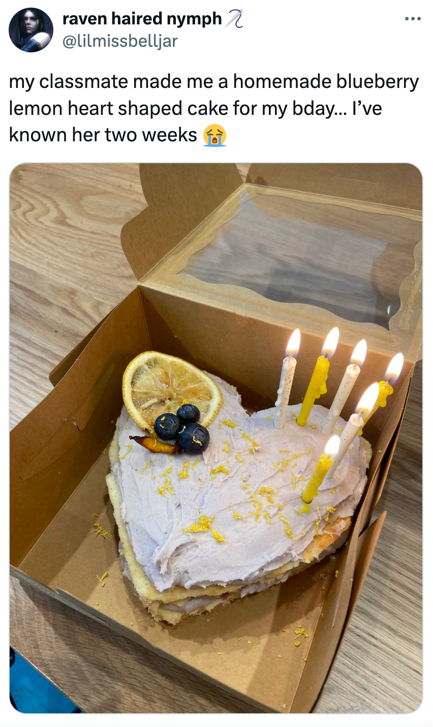 Kue lemon blueberry berbentuk hati dengan lilin, irisan lemon, dan blueberry di atasnya dalam kotak terbuka. Tweet berbagi kegembiraan atas hadiah ulang tahun yang penuh arti