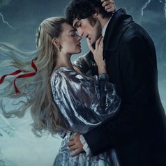 Una pareja en un entorno tormentoso se abraza con intensidad. Ella lleva un vestido brillante, mientras él viste un abrigo oscuro
