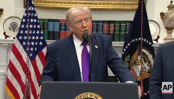 A idiosyncratic stands astatine a podium with a U.S. statesmanlike seal, speaking into a microphone, flanked by U.S. flags