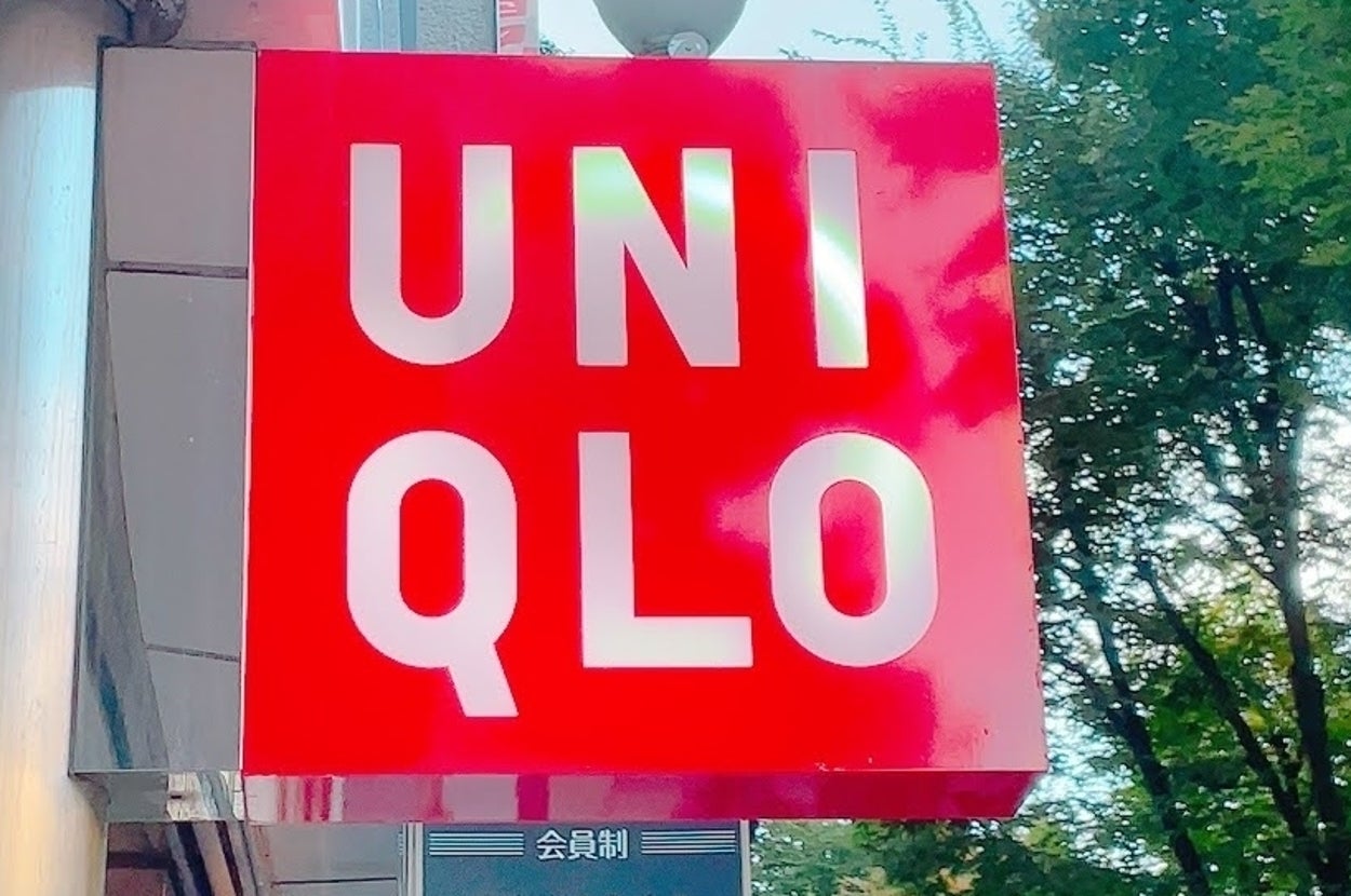 Uniqlo store sign with white lettering on a red background, surrounded by trees and building exterior