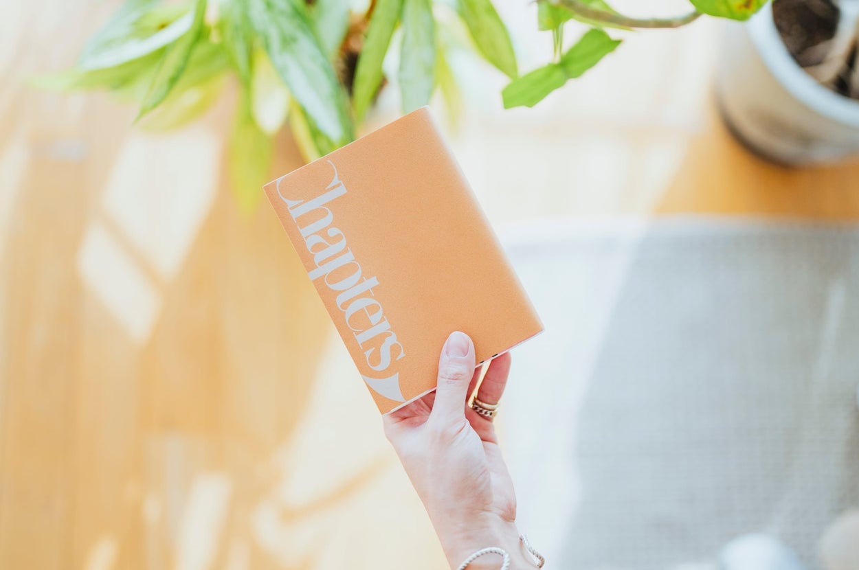 手に持たれた本「Chapters」。背景に観葉植物が見える。