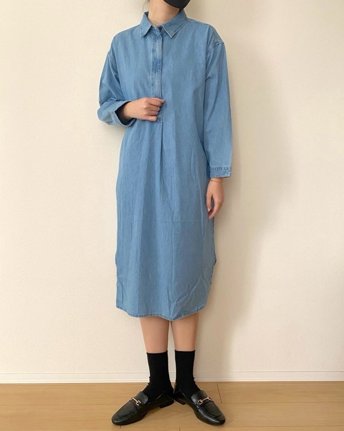無印良品の「婦人 カポック混 ライトデニム 長袖ワンピース」女性がデニムシャツドレスと黒い靴を履いて立っている。
