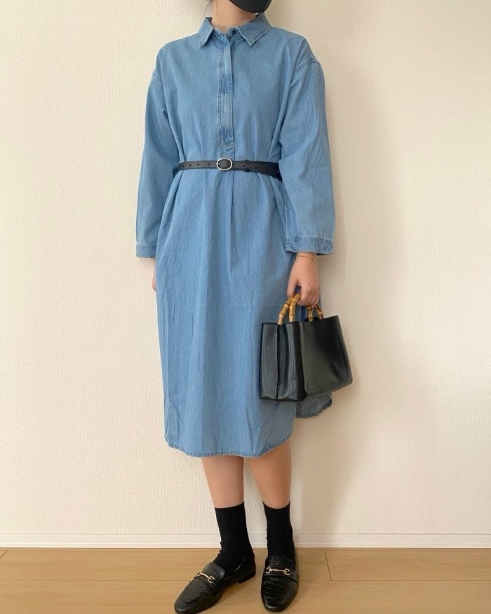 無印良品の「婦人 カポック混 ライトデニム 長袖ワンピース」女性がシンプルな長袖デニムワンピースを着て、黒いベルトとバッグ、ローファーを合わせたカジュアルなスタイル。