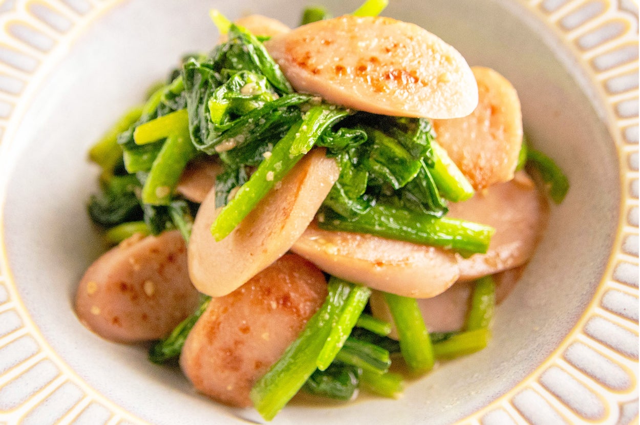 ソーセージと葉物野菜の炒め物が白い皿に盛り付けられている料理。