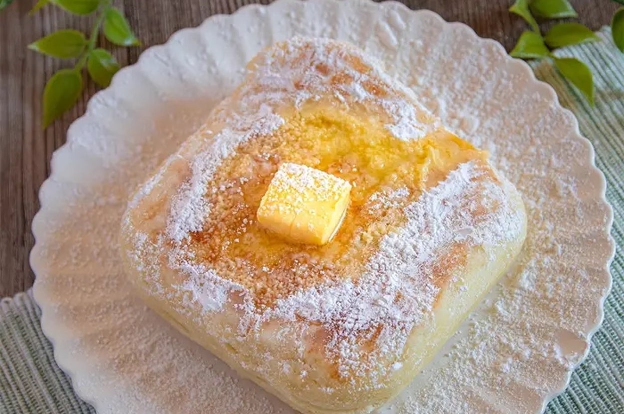 皿に盛られたパウダーシュガーがかかった四角いパンの上に、バターのかたまりがのっている。
