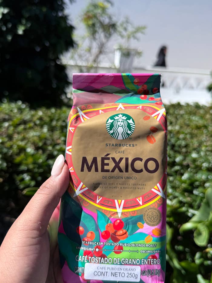 Persona sostiene paquete de café Starbucks México. Enfocado en "Starbucks Café México de Origen Único". Fondo natural desenfocado