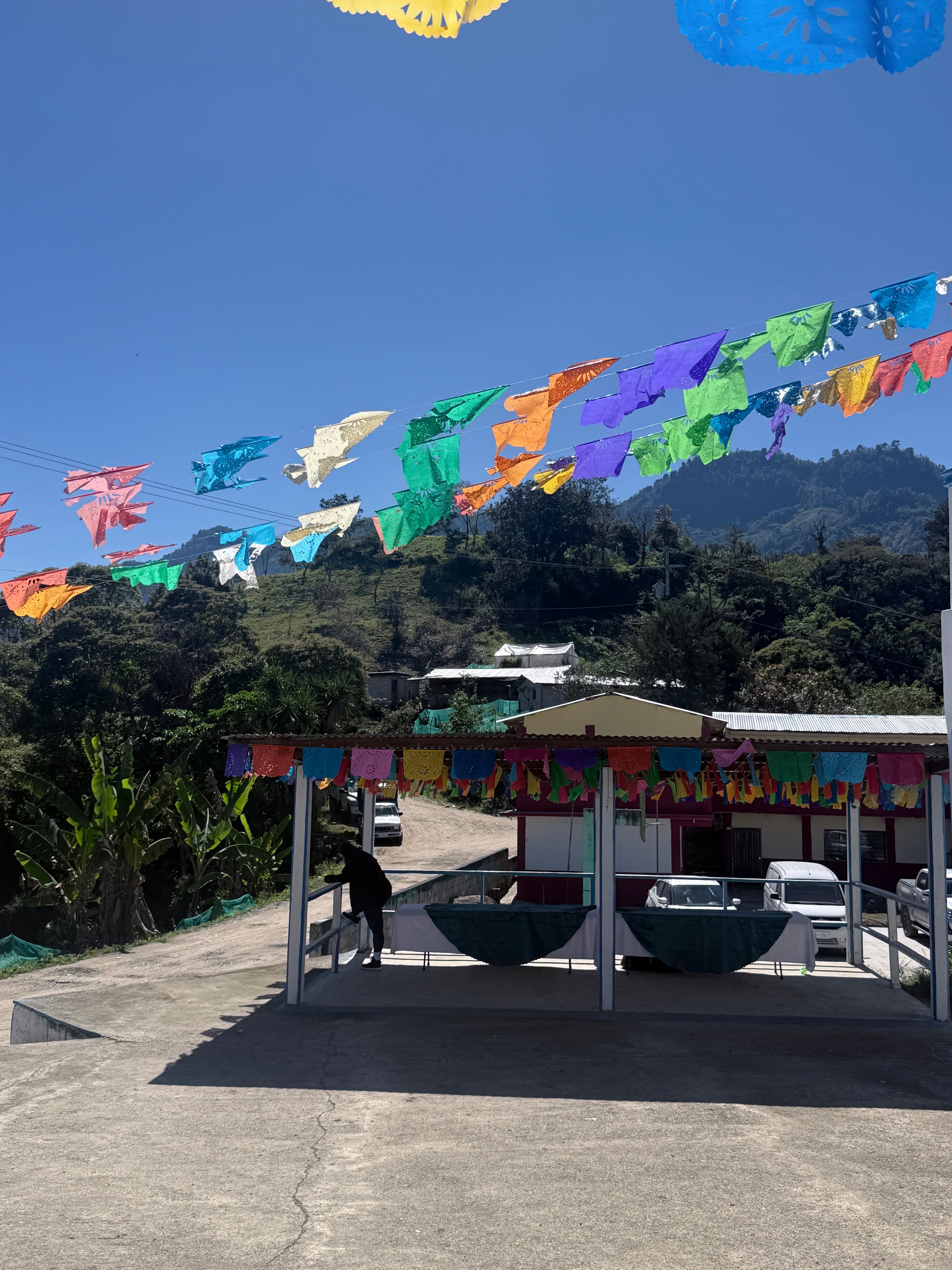 Banderines de papel picado decoran una calle en un ambiente montañoso y soleado