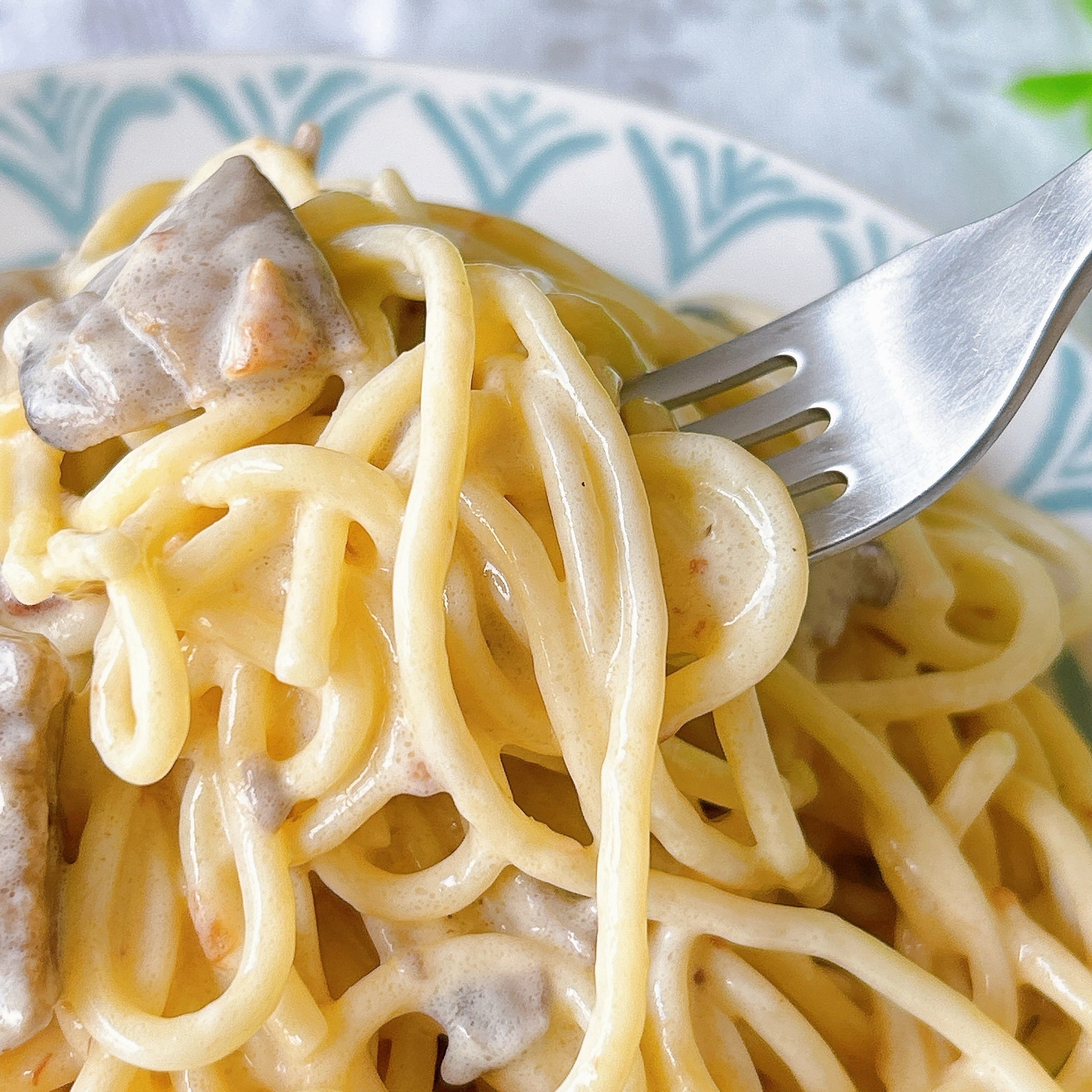 セブンイレブンの「7PG 金の3種きのこクリーム生パスタ」スパゲッティをフォークで持ち上げている様子