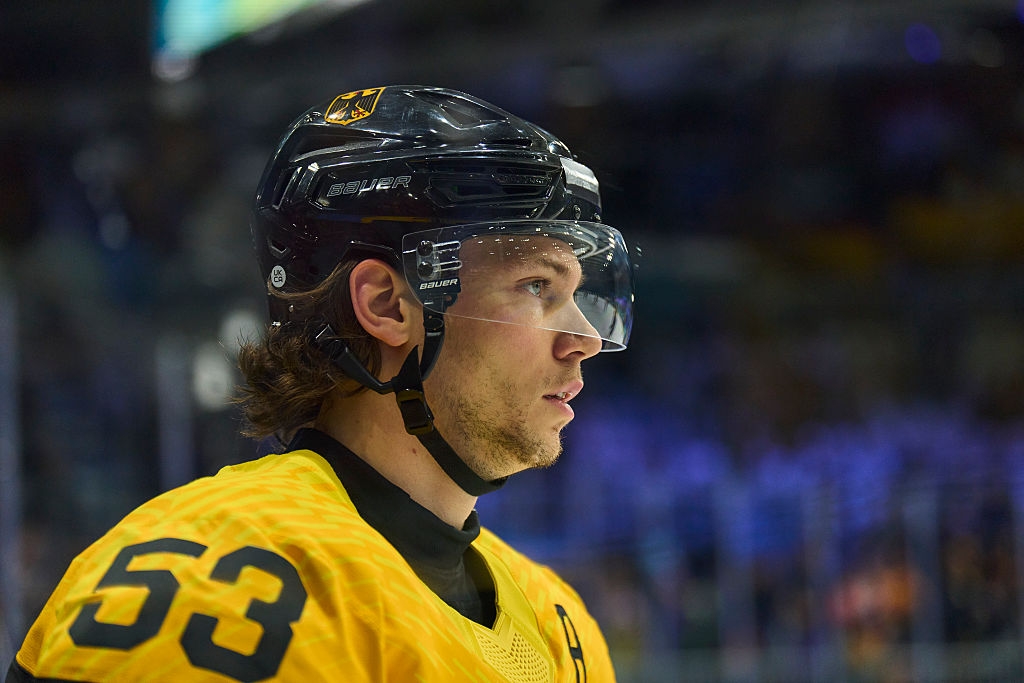 Hockeyspiller iført en gul trøye og hjelm med beskyttende visir, fokusert under en kamp