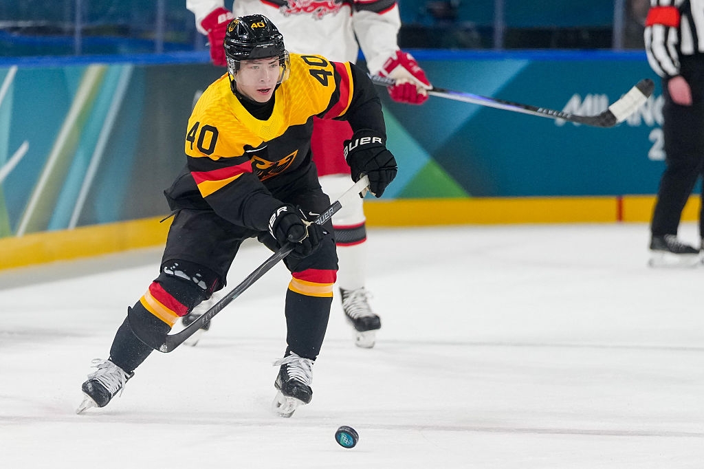 Hockeyspiller i svart og gul uniform med nummer 40 skøyter og håndterer pucken på is under en kamp