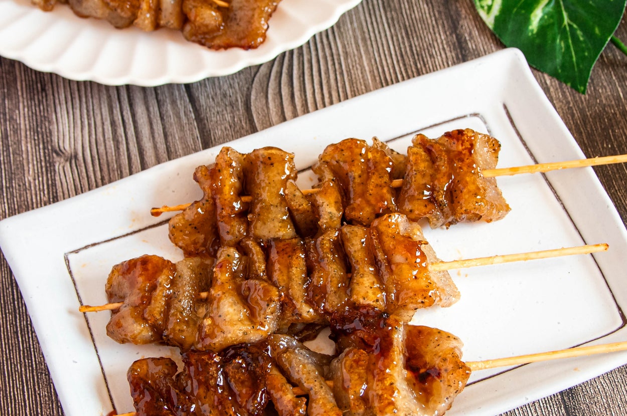 焼き鳥風のこんにゃくが白い皿に並び、木製のテーブルに置かれている。