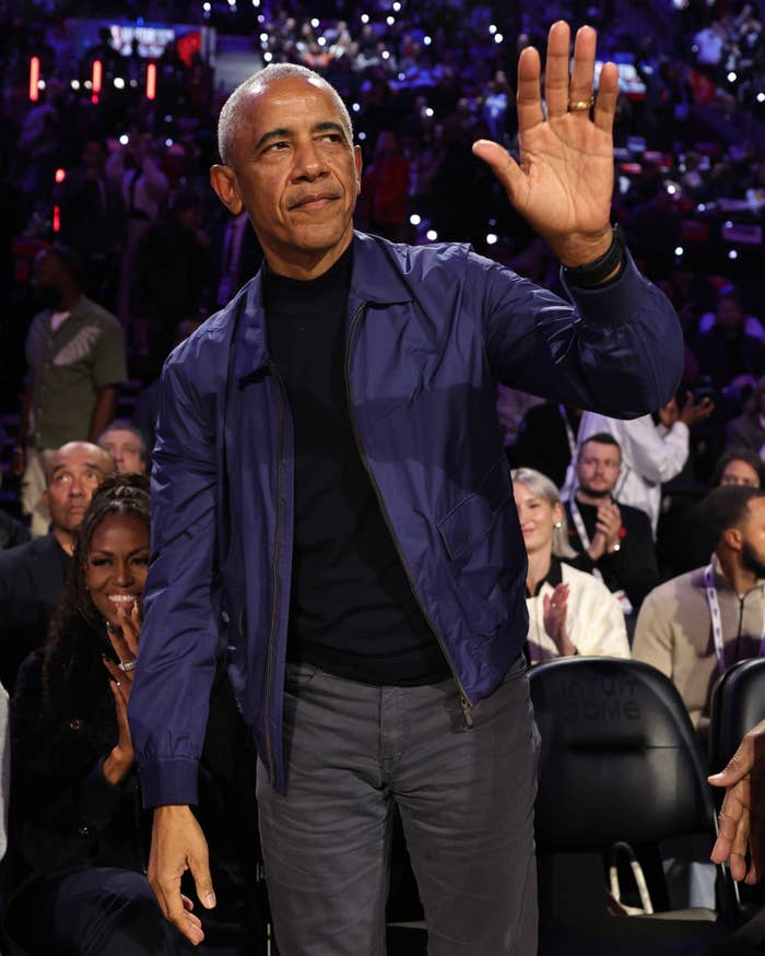 Person successful  a casual overgarment   waves to a cheering assemblage  astatine  an event, with others applauding successful  the background