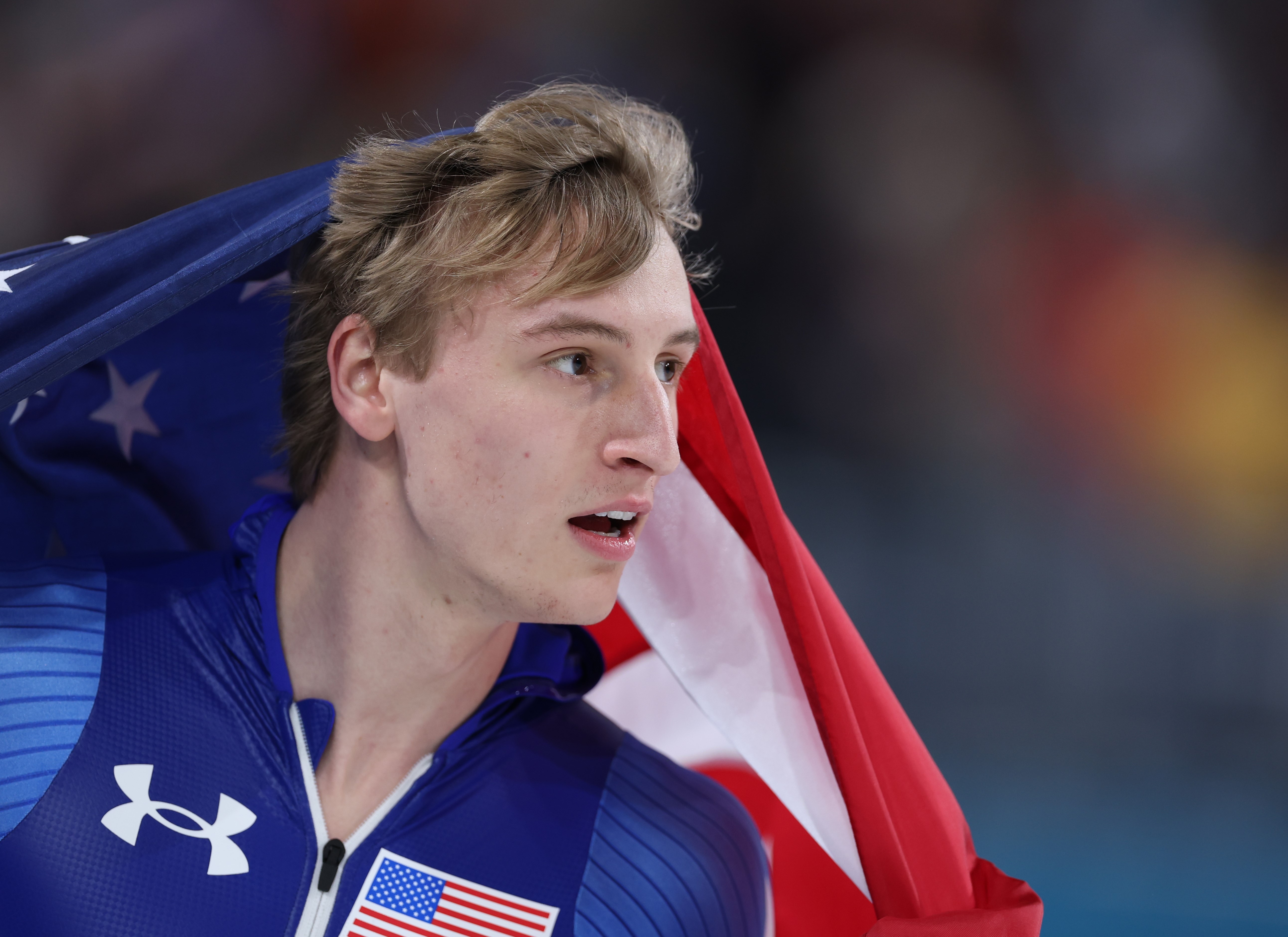 Athlete successful a bluish azygous with a U.S. emblem draped implicit his shoulders, looking to the broadside with an look of absorption and determination