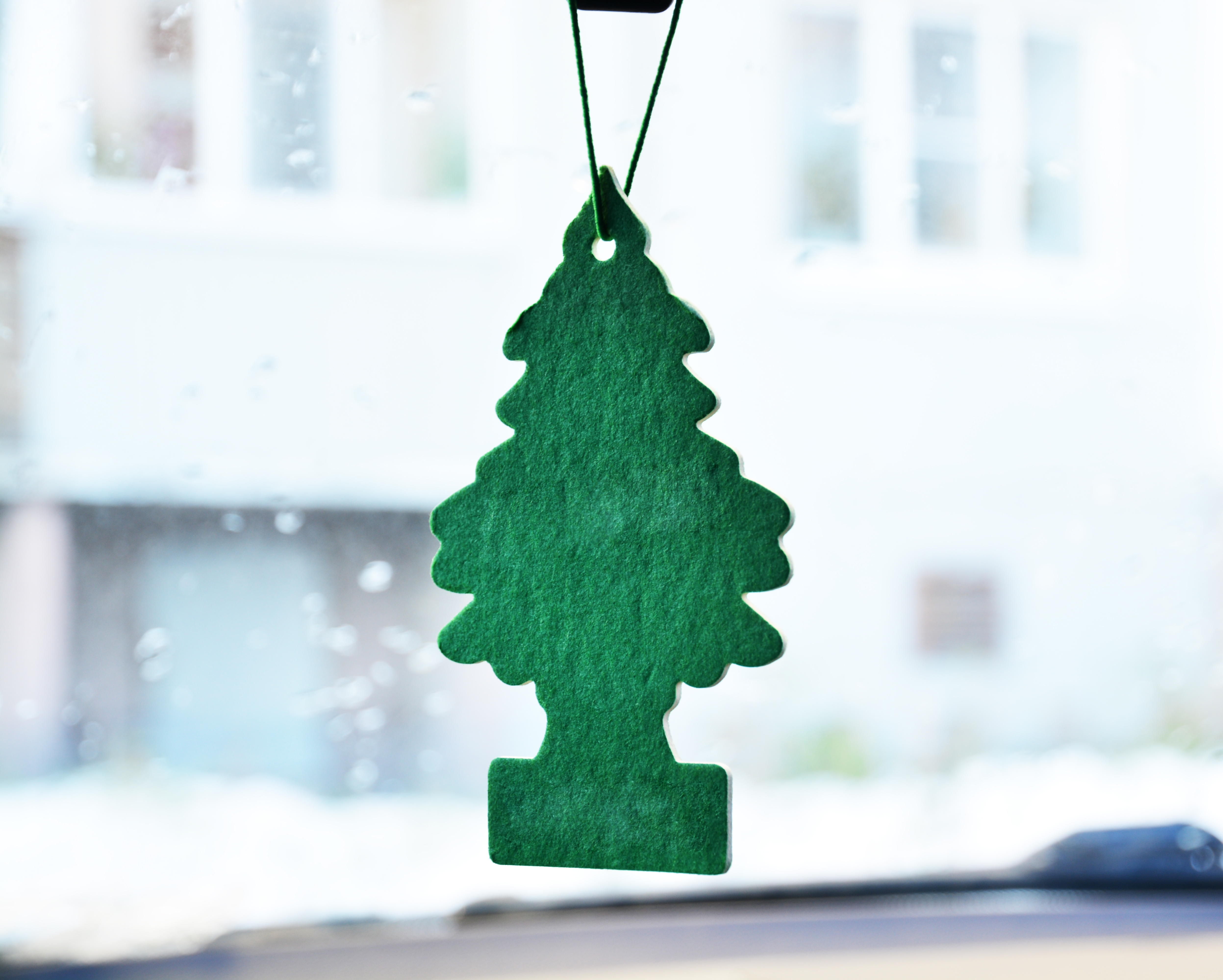 Tree-shaped air freshener hanging from a rearview mirror inside a car