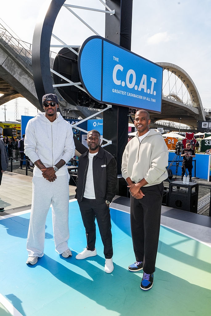 Three individuals basal   astatine  a sports event. Two are successful  casual diversion  wear, and 1  wears a overgarment   with a achromatic  shirt. A "C.O.A.T" motion   is down  them
