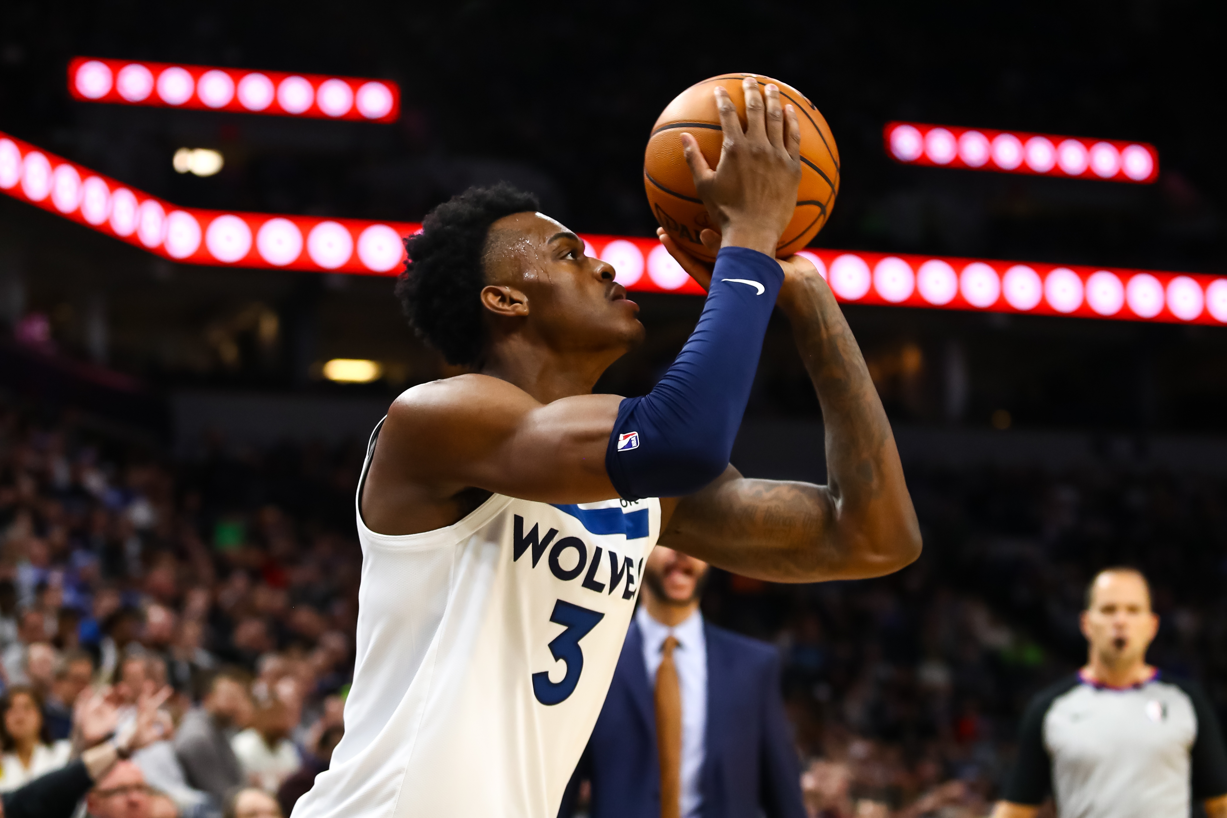 Basketball subordinate    successful  Wolves jersey prepares to sprout  during a game, with assemblage  and referee successful  the background