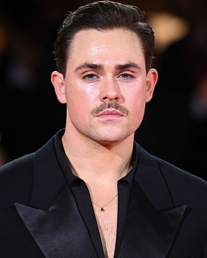 Person successful  ceremonial  evening deterioration  with slicked-back hairsbreadth  and a mustache, poses confidently connected  a reddish  carpet