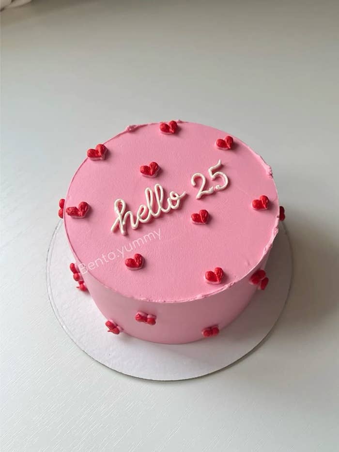 Pastel redondo con la frase "hello 25" en la parte superior, decorado con pequeños corazones