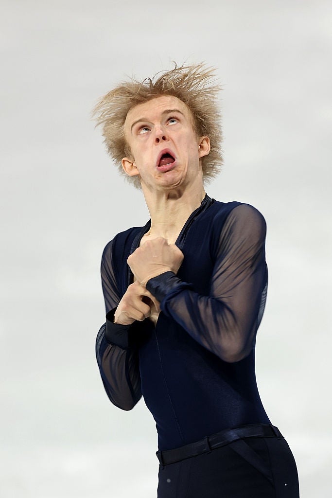 A figure skater mid-performance with an intense expression, wearing a fitted, long-sleeved outfit