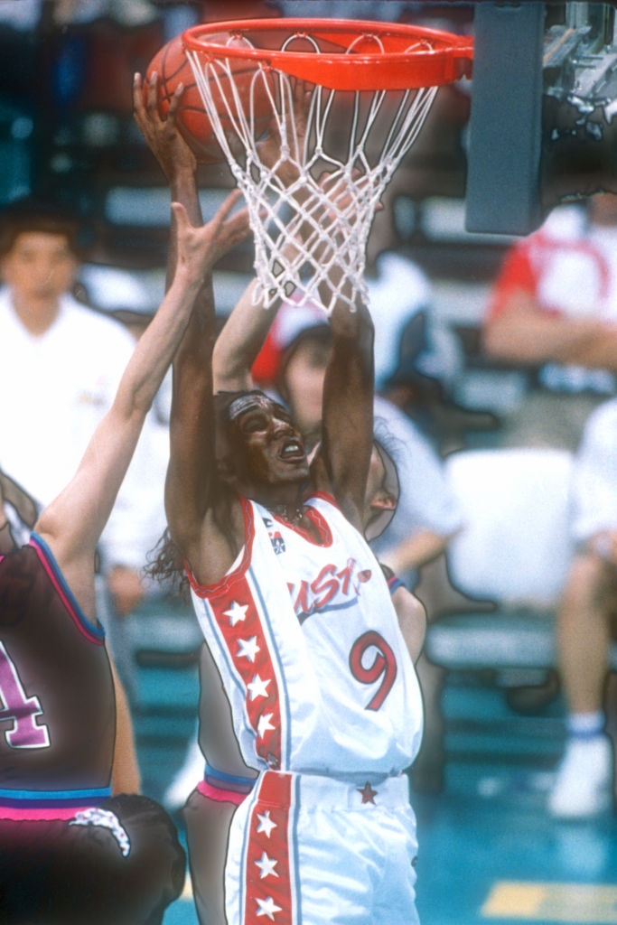 Basketball subordinate wearing a USA jersey, fig 9, making a dunk changeable during a game, with different players attempting to block