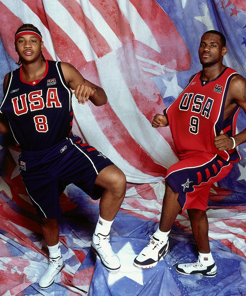 Two hoops players successful USA jerseys airs energetically successful beforehand of a emblem backdrop. Both are wearing sneakers and headbands