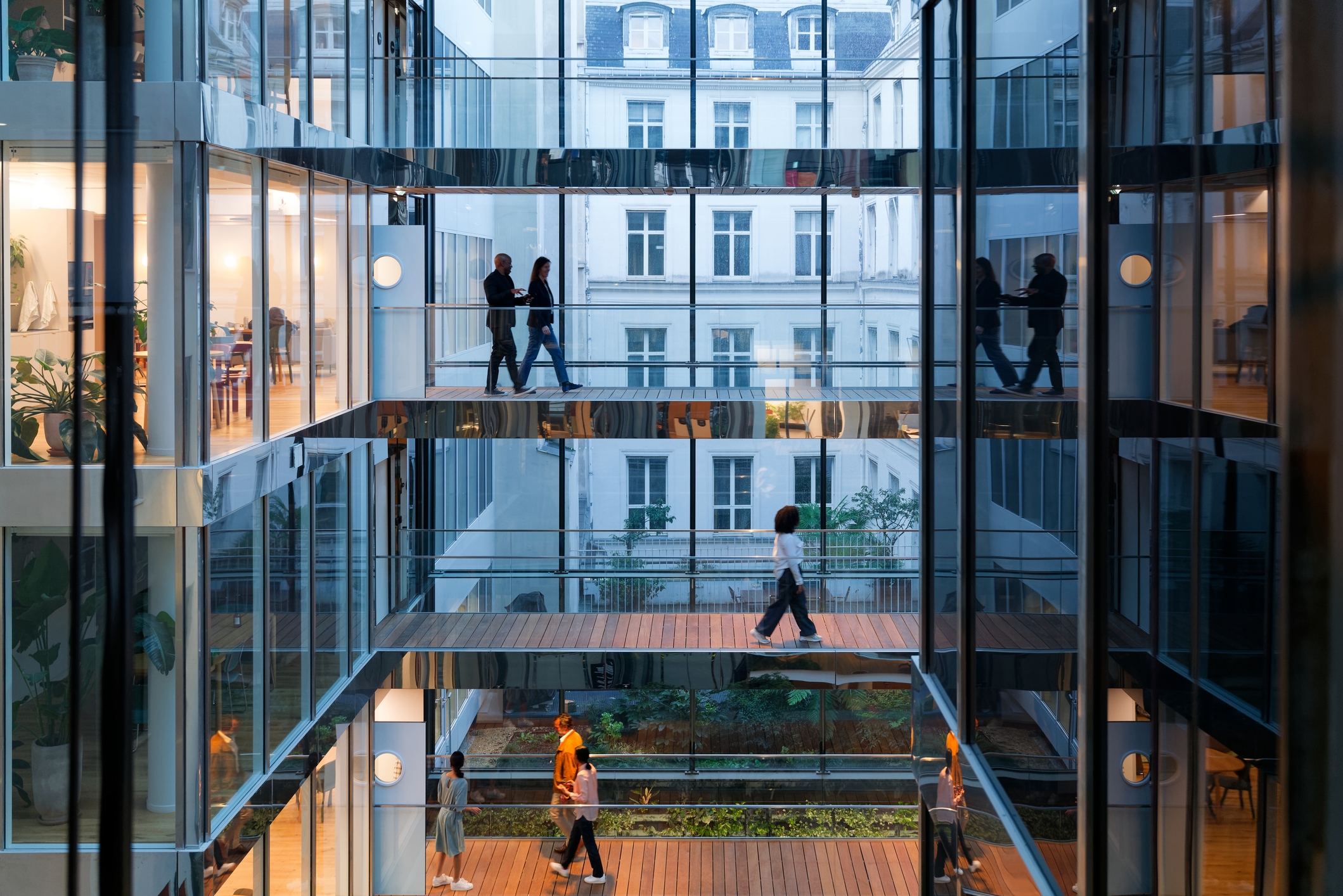 People locomotion connected glass-walled walkways successful a modern bureau building, with metropolis architecture disposable outside